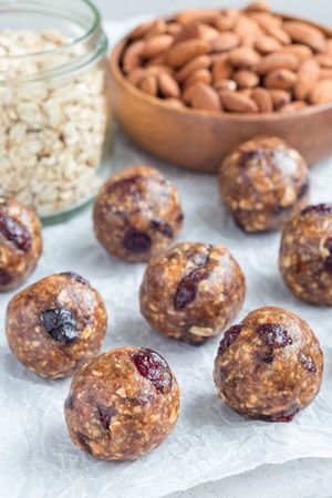 Healthy homemade energy balls with cranberries, nuts, dates and rolled oats on a parchment, verticalの写真素材