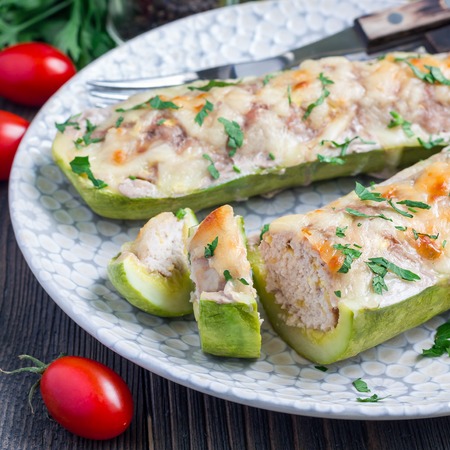 Zucchini boats stuffed with ground meet and topped with cheese on a plate, square formatの写真素材
