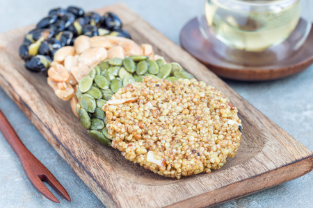 Korean traditional sweet snacks with peanuts, pumpkin seeds, black soybeans and chinese buckwheat on a wooden plate, horizontalの写真素材
