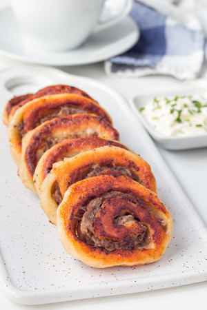 Fried savoury cottage cheese pies with minced meat on a white plate, served with yogurt, vertical