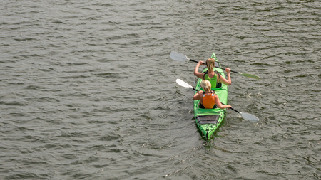 Two blondy woman sitting in a kayak, paddling in the sea water, back view, horizontal, copy spaceの写真素材