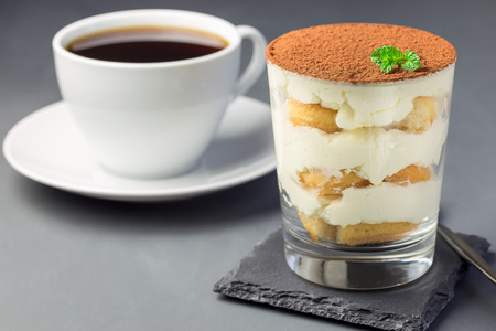 Traditional italian Tiramisu dessert cake in glass, decorated with cocoa powder and mint, on gray background, horizontalの写真素材