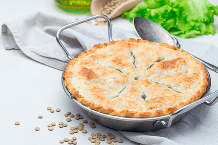 Vegetarian pot pie with lentil, mushrooms, potato, carrot and green peas, covered with puff pastry, in baking dish, horizontalの写真素材