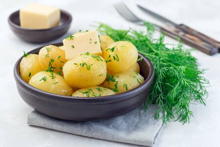 New young boiled potato topped with melted butter and chopped dill in ceramic bowl, horizontalの写真素材