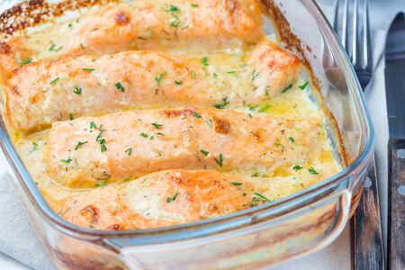 Baked in creamy sauce salmon in a glass baking dish, horizontal, closeupの写真素材