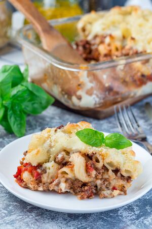 Macaroni casserole with ground beef, cheese and tomato on a white plate, verticalの写真素材