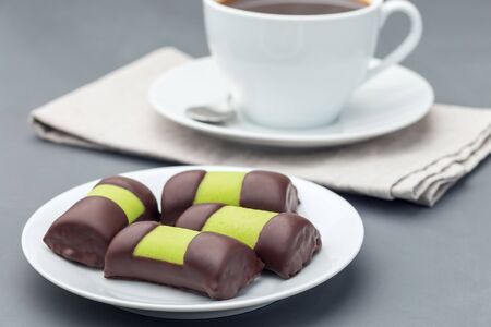 Swedish sweets punsch rolls or punschrullar, covered with green marzipan, on a white plate, served with coffee,  horizontalの写真素材