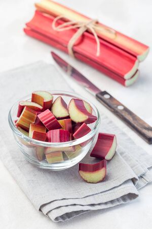 Cutted rhubarb in a glass dish, whole sticks on background,  verticalの写真素材