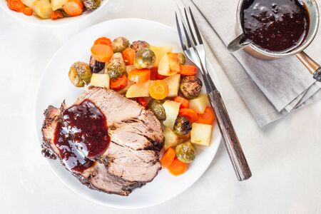 Pork shoulder in honey parmesan and soy souse, prepared in slow cooker or crockpot, served with carrot, potato and brussel cabbage, on a white plate, horizontal, top viewの写真素材