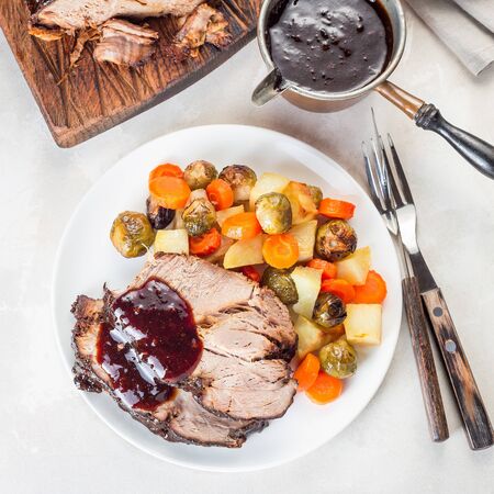Pork shoulder in honey parmesan and soy souse, prepared in slow cooker or crockpot, served with carrot, potato and brussel cabbage, on a white plate, top view, square formatの写真素材