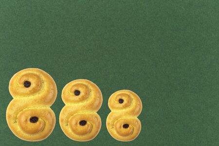 Traditional Swedish and scandinavian Christmas saffron buns Lussekatter on a green background,...