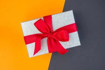 Yellow and black paper texture, silver glitter gift box with red ribbon on it, background for a template, horizontalの写真素材