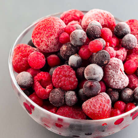 Frozen berries in a glass bowl, raspberry, strawberry, cranberry and black currant, square format, closeupの写真素材