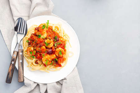 Shrimp linguine Puttanesca pasta with shrimps in spicy tomato basil sauce,  on  white plate, horizontal, top view, copy spaceの写真素材