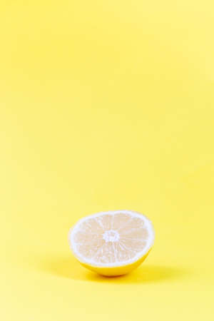 Piece of lemon on a yellow background, vertical, copy spaceの写真素材
