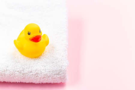 One rubber duck on a white terry bath towel, pink background with place for copy space, horizontalの写真素材