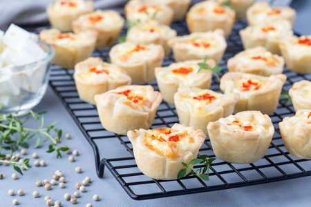 Mini quiche muffins with feta cheese, fried onion, thyme and red bell pepper, on a cooling rack,  horizontalの写真素材