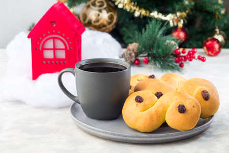 Traditional Swedish and scandinavian Christmas saffron buns Lussekatter with cup of coffee, Christmas decoration on a background, horizontalの写真素材