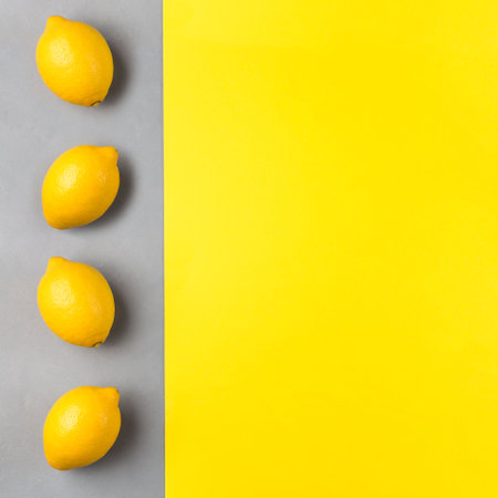 Colors of year 2021, yellow paper and gray concrete texture, fresh lemons on gray background, square formatの写真素材