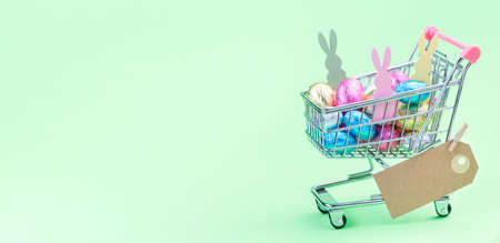 Banner with shopping tray or basket full of colorful chocolate candy eggs and Easter bunnies, paper...