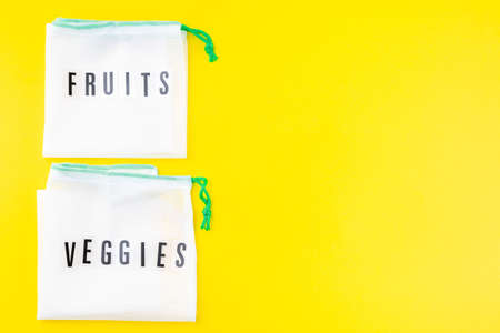 Reusable bags for fruits and vegetables on a yellow background, zero waste or plastic free concept, horizontal, top view, copy spaceの写真素材