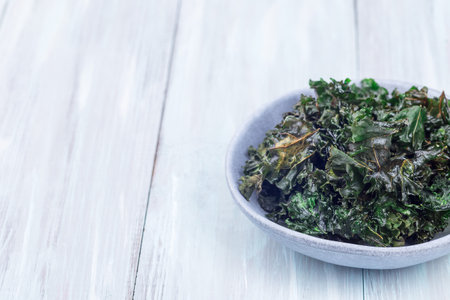 Three ingredient baked green kale chips with sea salt and olive oil, in a gray bowl, horizontal, copy spaceの写真素材