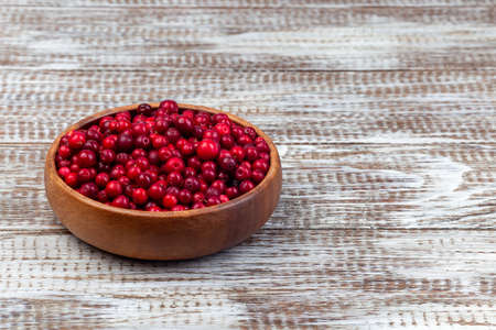 Bowl of fresh cranberry on a wooden background, horizontal, copy spaceの写真素材