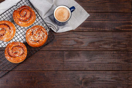 Traditional Swedish cinnamon buns Kanelbulle with cup of coffee or cappuccino, on a wooden background, horizontal, top view, copy spaceの写真素材