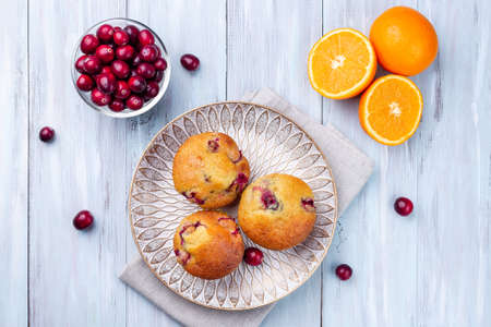 Homemade cranberry orange muffins on wooden plate, horizontal, top viewの写真素材