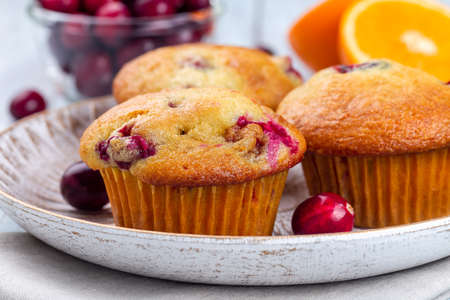 Homemade cranberry orange muffins on wooden plate, horizontal, closeupの写真素材