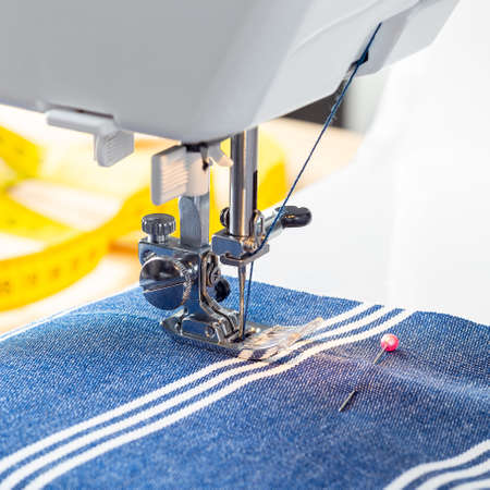 Sewing machine with striped blue white fabric and thread, home crafting or hobby, square format