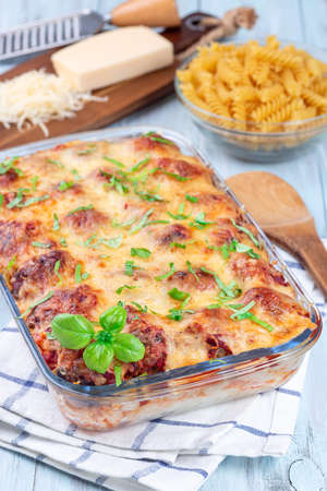 Mac and cheese with meatballs, mozzarella, tomato sauce and basil, in backing dish, verticalの写真素材