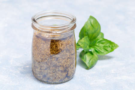 Traditional basil green pesto sauce in glass jar, on light blue background, horizontalの写真素材