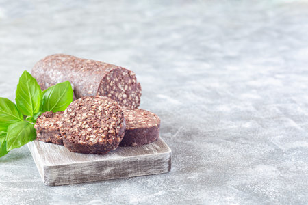 Traditional Irish and British black pudding sausage slices on a wooden board, horizontal, copy space
