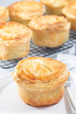 Small beef pot pies on plate and cooling rack, vertical