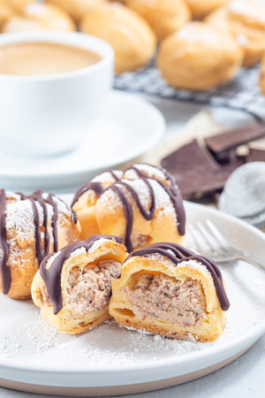 Profiteroles with whipped cream and chocolate filling, with melted chocolate, cutted, vertical