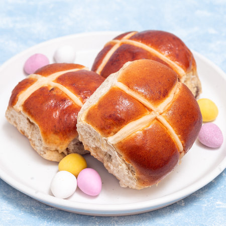 Traditional easter food freshly baked hot cross buns on plate with chocolate candy eggs, squareの写真素材