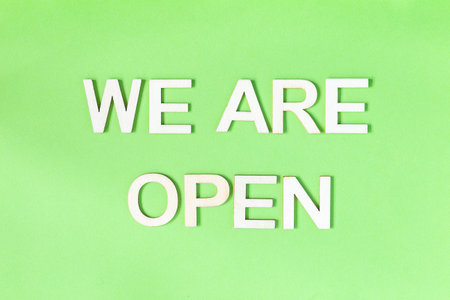 We are open quote, welcome sign for business or caffe, wooden letters on green background