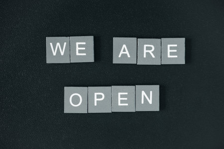 We are open quote, welcome sign for business or caffe, wooden letters on black background