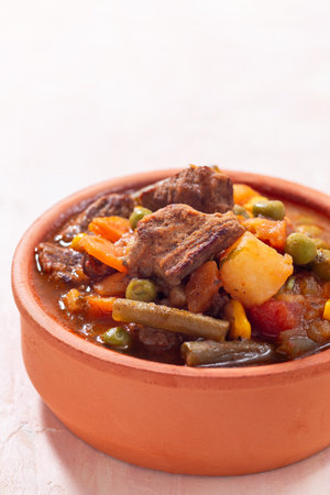 Delicious beef stew with potato, green beans, carrot, peas and corn, in ceramic bowl, verticalの写真素材
