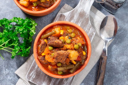Homemade beef stew with potato, green beans, carrot, peas and corn, in ceramic bowl, horizontal, topの写真素材