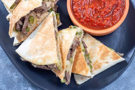 Mexican fajita quesadilla with pieces of beef steak, green bell pepper, onion and cheese, top viewの写真素材