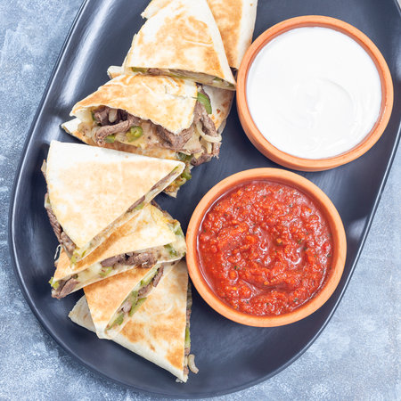 Mexican fajita quesadilla with pieces of beef steak, bell pepper, onion, cheese, top view squareの写真素材