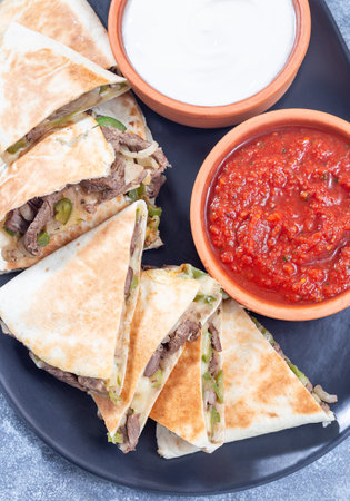 Mexican fajita quesadilla with pieces of beef steak, bell pepper, onion, cheese, top view verticalの写真素材