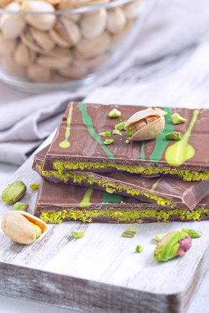 Dubai style milk chocolate bar with pistachio and kadaifi filing, lying on cutting board, verticalの写真素材