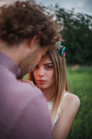 The curly-haired guy with the red-haired girl with freckles on the background of fabulous scenery of city and nature. Lovely couple of lovers on a walk in the city and nature. Tenderness, emotionの写真素材