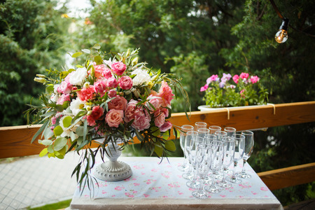 bright bouquet of peony on the wedding table with glasses on a green backgroundの写真素材