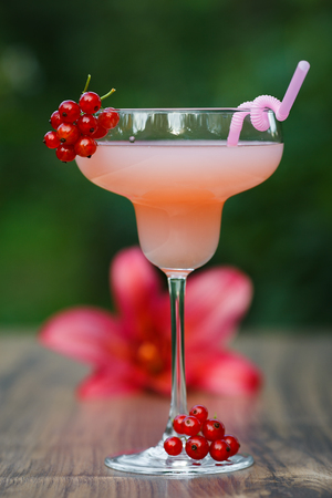 Glass of cold pink cocktail with straw on green background bokehの写真素材