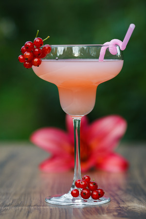 Glass of cold pink cocktail with straw on green background bokehの写真素材