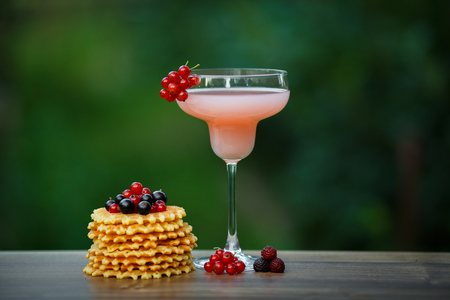Glass of cold pink cocktail on green background bokehの写真素材
